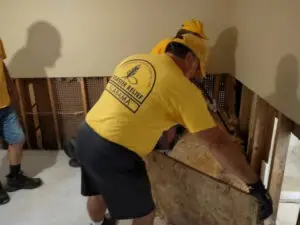 Two Alabama Baptist Disaster Relief volunteers rip up flooring using crowbars